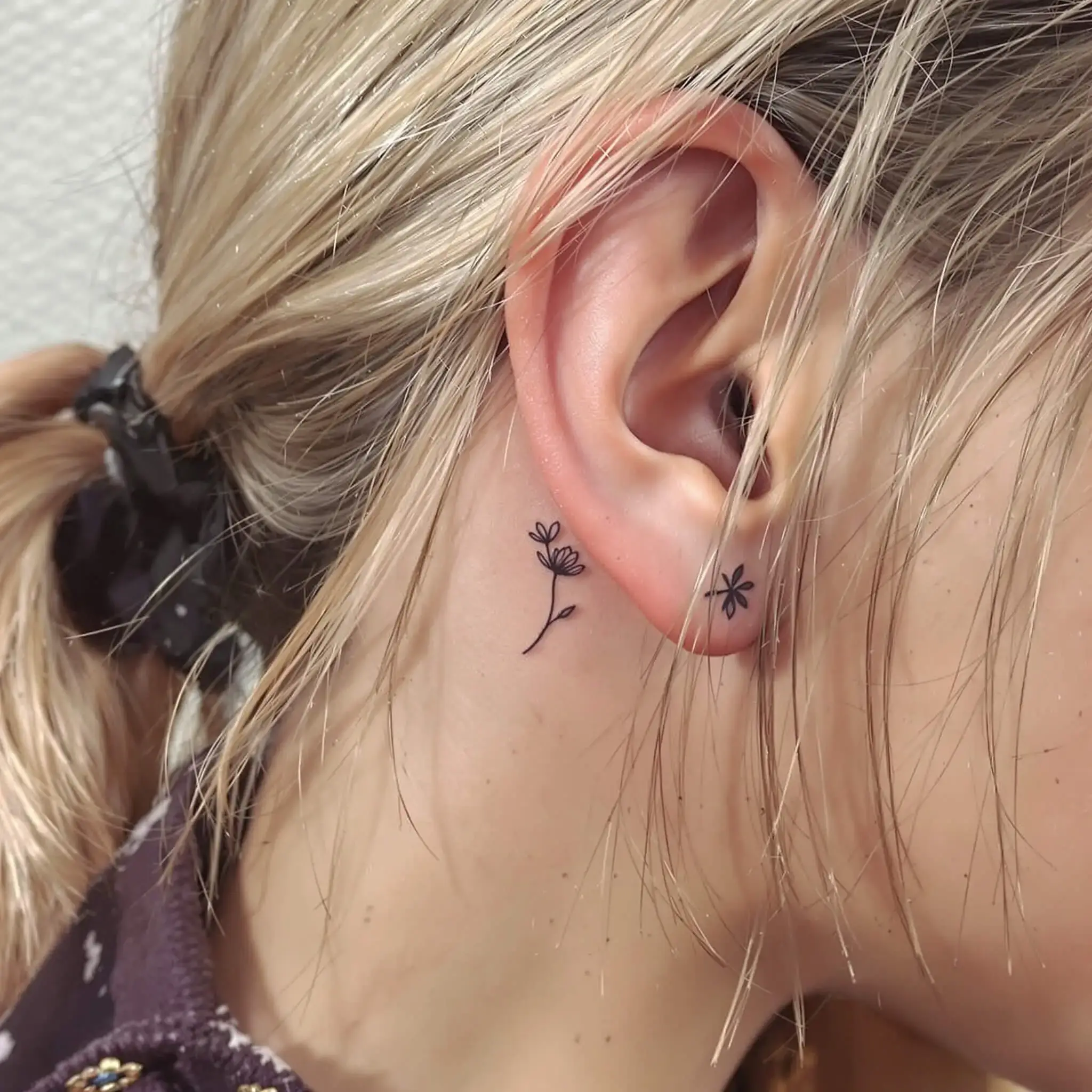 Micro flower tattoo behind ear