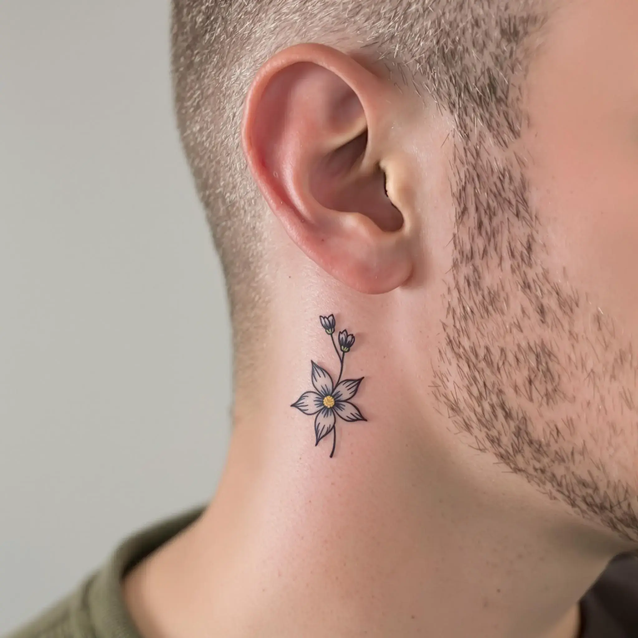 Un autre petit tatouage de fleur derrière l'oreille d'un homme